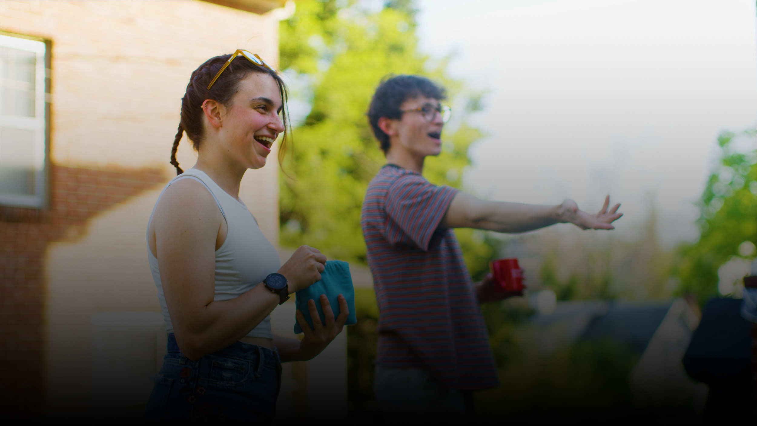 A blurred portrait of a girl and a boy playing cornhole.