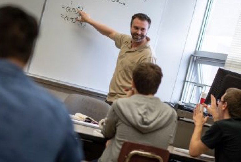 A University of Wise faculty member teaching at a white board