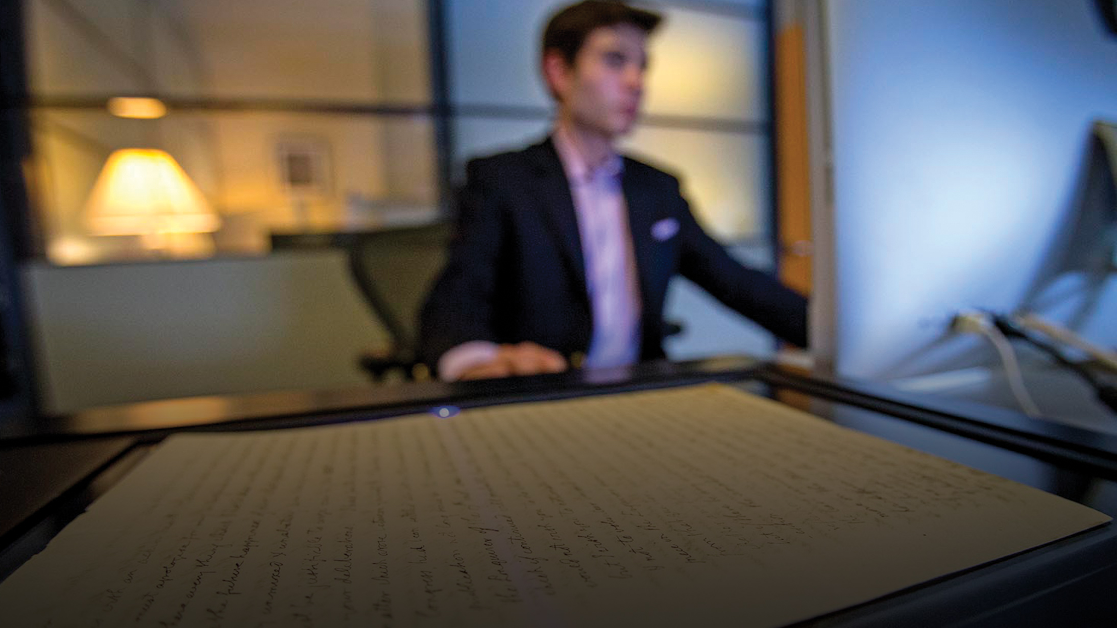 A blur portrait of a person scanning a documents for preservation.